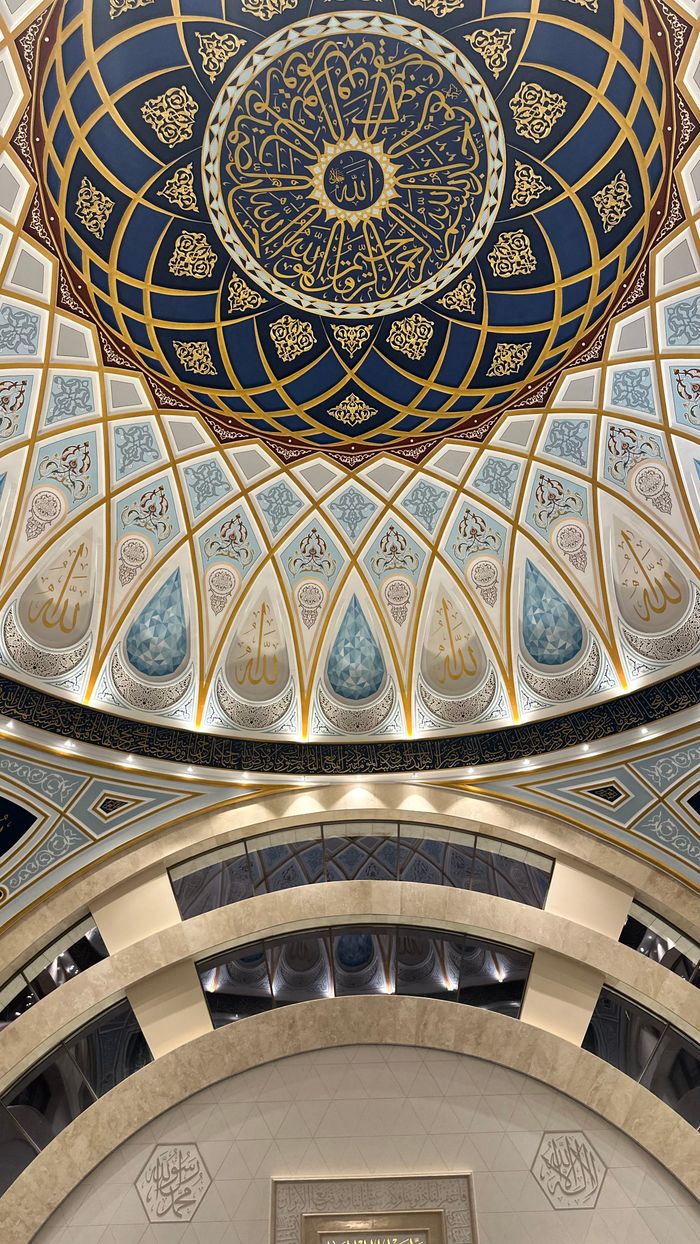 A beautifully detailed view of an elaborate mosque ceiling showcasing Islamic art and calligraphy.
