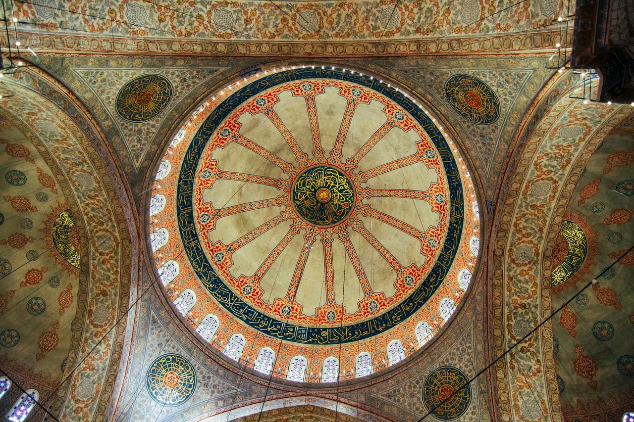 Beautifully detailed dome interior showcasing intricate Islamic art and calligraphy.