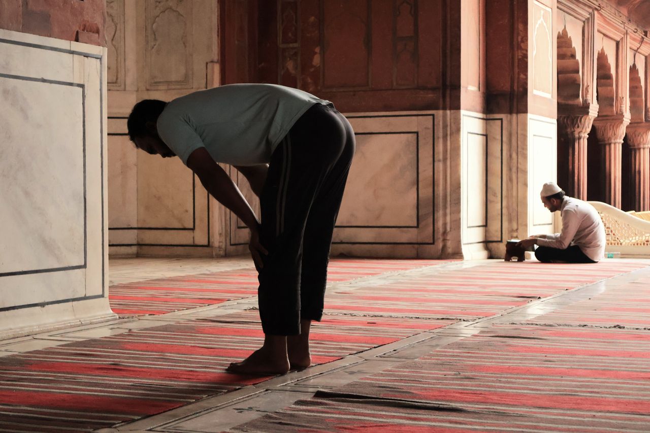 Two men praying inside the historic Jama Masjid in Delhi, India, highlighting spirituality and tradition.