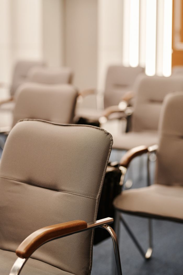 Modern beige armchairs in an empty conference room setting, vertical shot.