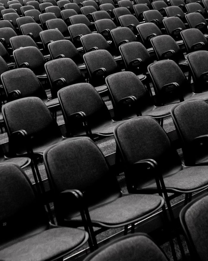 Monochrome image of empty auditorium seats in a classic pattern.